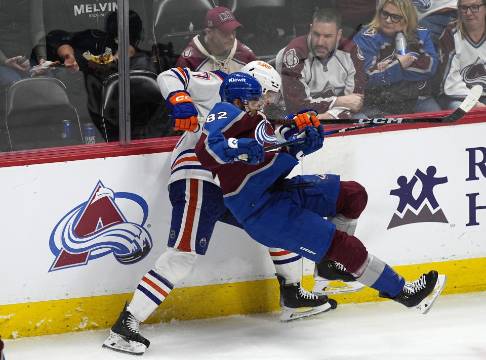 Colorado Avalanche defenseman Caleb Jones, front, falls while working for control of the puck against Edmonton Oilers defenseman Brett Kulak during the third period of an NHL hockey game Thursday, April 18, 2024, in Denver. (AP Photo/David Zalubowski)