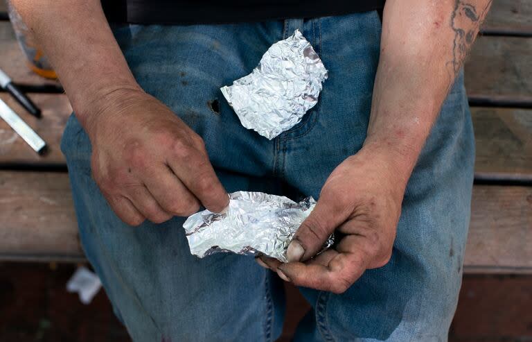 ARCHIVO - Un hombre se prepara para fumar fentanilo en la banca de un parque el jueves 18 de mayo de 2023, en el centro de Portland, Oregon. (Beth Nakamura/The Oregonian vía AP, Archivo)