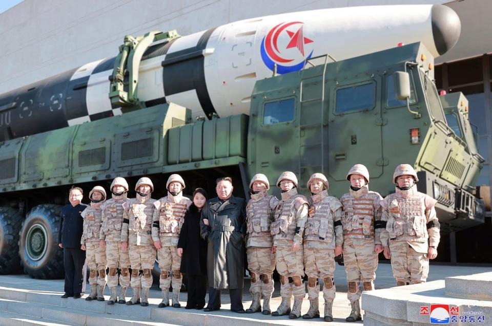 North Korean leader Kim Jong Un, center, and his daughter, center left, pose with soldiers for a photo, in front of what it says a Hwasong-17 intercontinental ballistic missile, at unidentified location in North Korea (Associated Press/ KCNA)