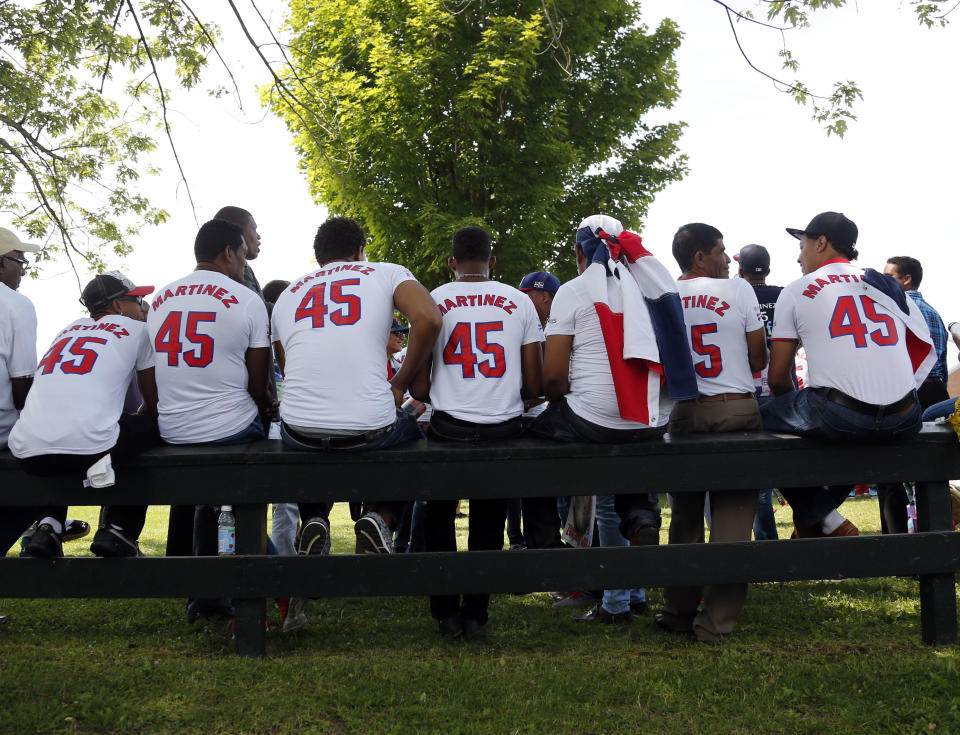 Pedro Martinez fans sit on a fence at the Clark Sports Center before the National Baseball Hall of Fame induction ceremony on Sunday, July 26, 2015, in Cooperstown, N.Y. Martinez , along with Former Major League Baseball players Randy Johnson, Craig Biggio and John Smoltz will be inducted to the National Baseball Hall of Fame on Sunday. (AP Photo/Mike Groll)