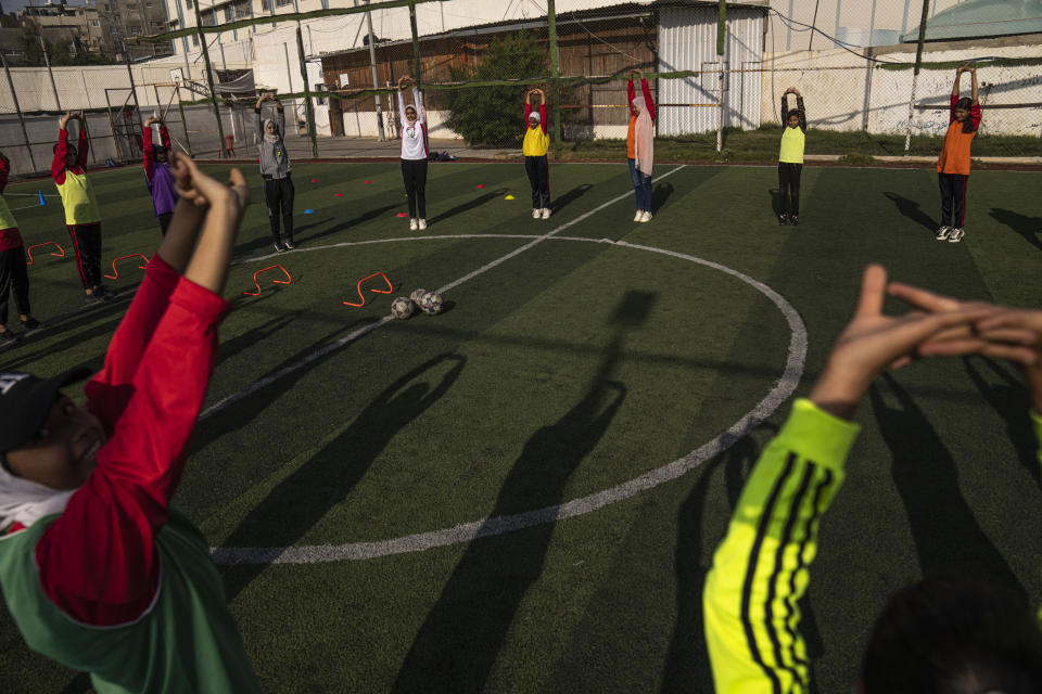 Palestinian girls stretch during a soccer training session at the Beit Hanoun Al-Ahli Youth Club's ground in the northern Gaza strip, Tuesday, Oct. 29, 2022. Women's soccer has been long been neglected in the Middle East, a region that is mad for the men's game and hosts the World Cup for the first time this month in Qatar. (AP Photo/Fatima Shbair)