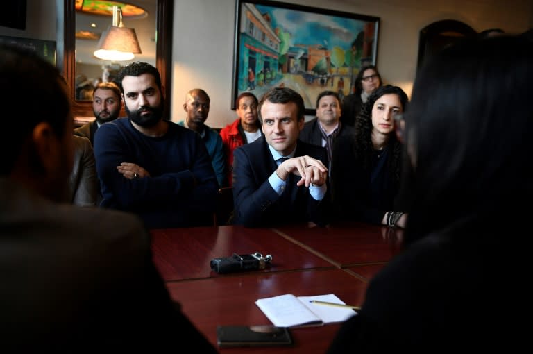 French presidential election candidate for the En Marche movement Emmanuel Macron (C) listens during a meeting organised in a bar in Les Mureaux on March 7, 2017