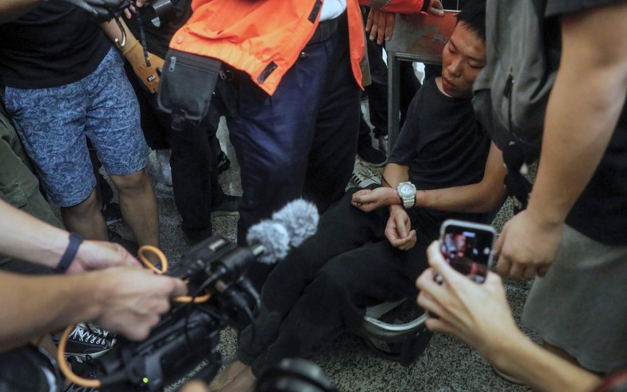 Cameramen and photographers film a detained man, who protesters claimed was a police officer from mainland China - AP