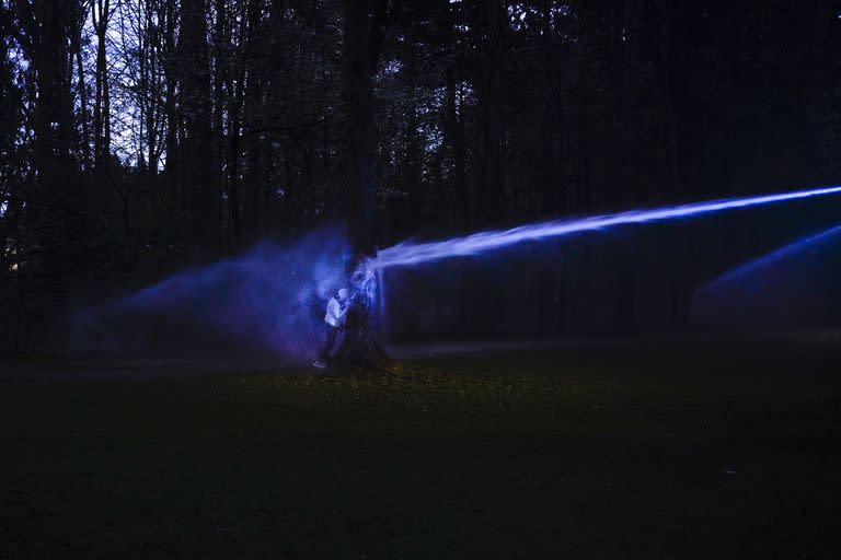 Un manifestante se refugia detrás de un árbol mientras la policía usa un cañón de agua para dispersar a un grupo de personas en el parque Bois de la Cambre en Bruselas, donde realizaron una reunión no autorizada a pesar de las restricciones del coronavirus el 2 de abril 
