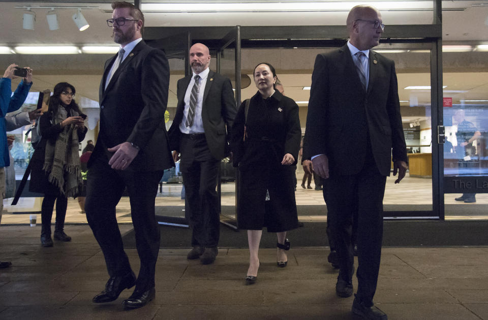 Meng Wanzhou, chief financial officer of Huawei, is flanked by security as she leaves B.C. Supreme Court in Vancouver, Thursday, January 23, 2020. Wanzhou is in court for hearings over an American request to extradite the executive of the Chinese telecom giant Huawei on fraud charges.(Jonathan Hayward/The Canadian Press via AP)