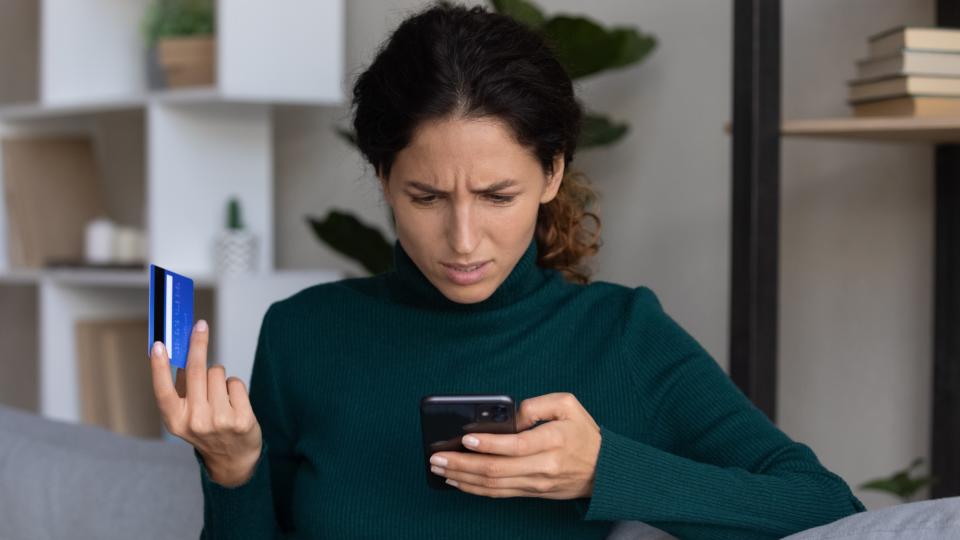 woman holding phone and credit card after being hacked