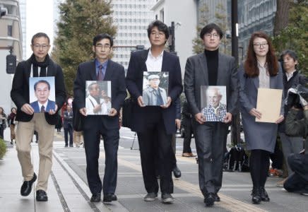 Lawyers and activists hold photos of South Korean plaintiffs who were forced to work for a Japanese firm during World War Two as they visit Nippon Steel & Sumitomo Metal Corp's headquarters building in Tokyo, Japan in this photo taken by Kyodo November 12, 2018. Mandatory credit Kyodo/via REUTERS