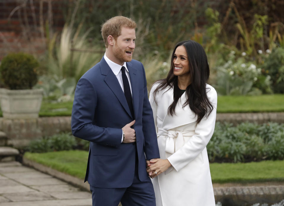 FILE - In this Monday Nov. 27, 2017 file photo, Britain's Prince Harry and his fiancee Meghan Markle pose for photographers in the grounds of Kensington Palace in London, after announcing their engagement. Prince Harry and his wife, Meghan, are fulfilling their last royal commitment Monday March 9, 2020 when they appear at the annual Commonwealth Service at Westminster Abbey. It is the last time they will be seen at work with the entire Windsor clan before they fly off into self-imposed exile in North America. (AP Photo/Matt Dunham, file)