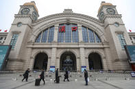 People walk past the closed Hankou Railway Station in Wuhan in central China's Hubei Province, Thursday, Jan. 23, 2020. Overnight, Wuhan authorities announced that the airport and train stations would be closed, and all public transportation suspended by 10 a.m. Friday. Unless they had a special reason, the government said, residents should not leave Wuhan, the sprawling central Chinese city of 11 million that's the epicenter of an epidemic that has infected nearly 600 people. (Chinatopix via AP)