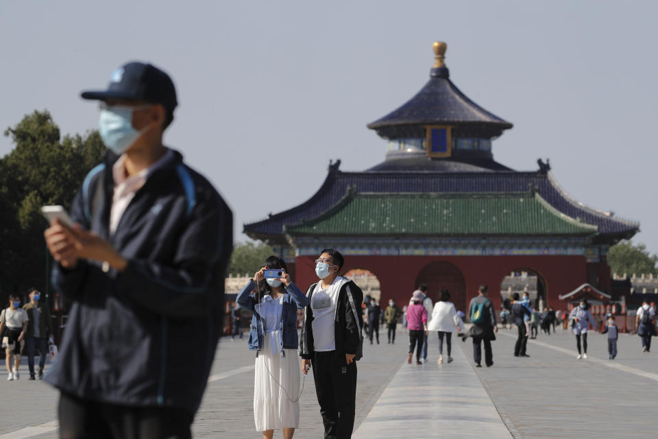 Visitors wearing protective face masks to help curb the spread of the new coronavirus visits the capital's popular tourist spot of Temple of Heaven in Beijing, Sunday, May 10, 2020. A family in China, nightclubs in South Korea and a slaughterhouse in Germany: New clusters of coronavirus infections are igniting concerns about a second wave even as calls grow in some countries to relax restrictions even further. (AP Photo/Andy Wong)