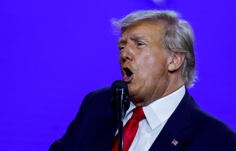 Former U.S. President Donald Trump, wearing a red tie, white shirt and dark suit bearing a flag pin, speaks during the Conservative Political Action Conference (CPAC).