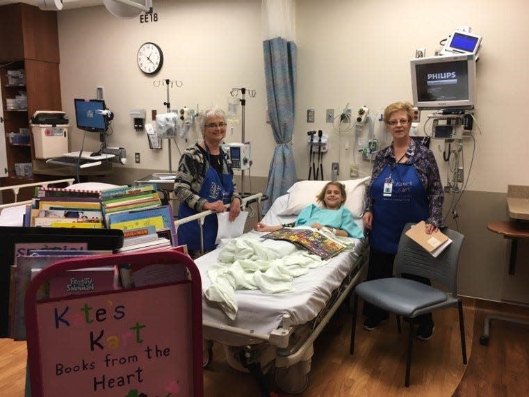 An 8-year-old Rhianna Booth receives books from two Kate’s Kart volunteers while in her hospital room during one of her two hospitalizations in 2016. Kate’s Kart has given away more than 450,000 books to children in its 15 years of life to help promote literacy and improve mental health.