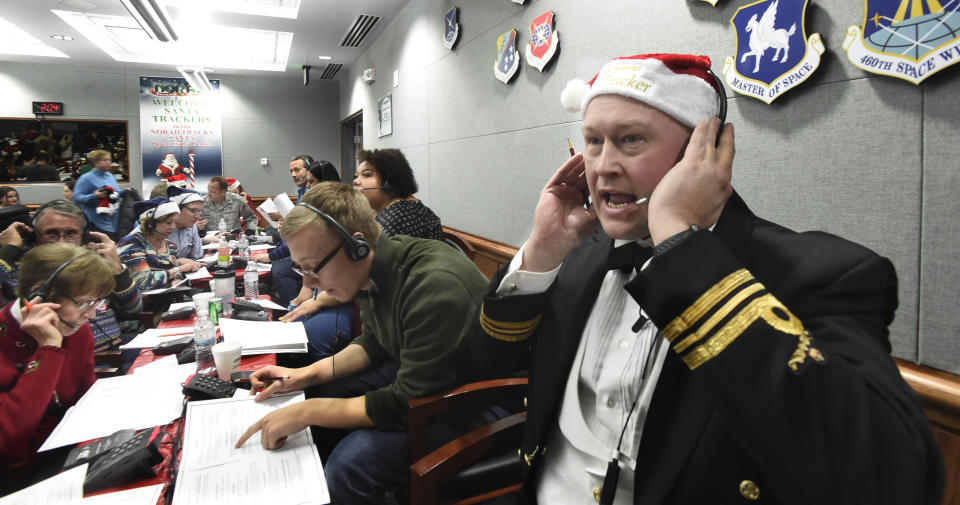 FILE – In this Dec. 24, 2017, file photo, Canadian Lt. Maj. Chris Hache takes a call while volunteering at the NORAD Tracks Santa center at Peterson Air Force Base in Colorado Springs, Colo. Hundreds of volunteers will help answer the phones again when the program resumes on Monday, Dec. 24, 2018, for the 63rd year. Children from around the world call to ask when Santa Claus will get to their house. (Jerilee Bennett/The Gazette via AP, File)