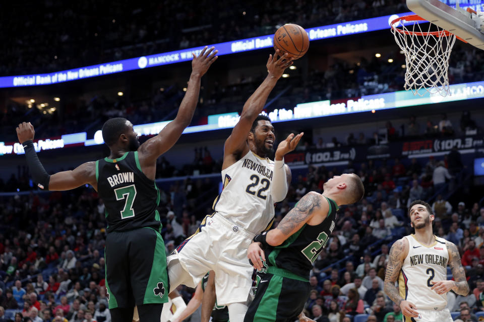 New Orleans Pelicans center Derrick Favors (22) is fouled as he goes to the basket between Boston Celtics guard Jaylen Brown (7) and center Daniel Theis in the first half of an NBA basketball game in New Orleans, Sunday, Jan. 26, 2020. (AP Photo/Gerald Herbert)