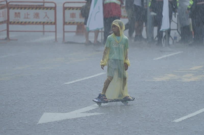 全台各地近來午後常降豪雨、圖為小朋友在大雨中滑蛇板／中央社