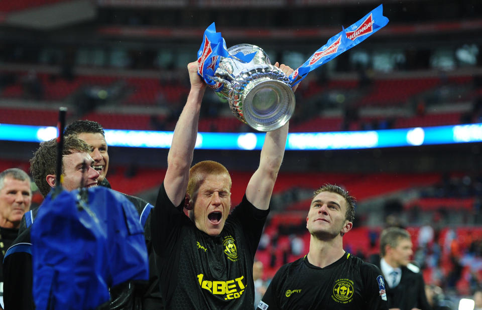 Match-winner Ben Watson celebrates with the FA Cup after Wigan beat Manchester City (Photo credit should read ANDREW YATES/AFP/Getty Images)