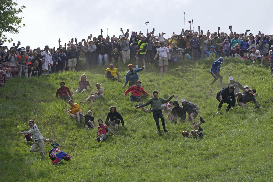Participants compete in the men's downhill race during the Cheese Rolling contest at Cooper's Hill in Brockworth, Gloucestershire, Monday, May 29, 2023. The Cooper's Hill Cheese-Rolling and Wake is an annual event where participants race down the 200-yard (180 m) long hill chasing a wheel of double gloucester cheese. (AP Photo/Kin Cheung)