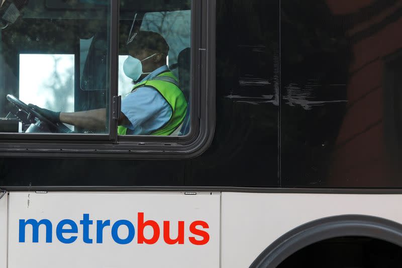 FILE PHOTO: A Washington Metro bus driver passes along a route wearing a face mask, as Mayor Muriel Bowser issued a State of Emergency in response to the coronavirus disease (COVID-19) in Washington