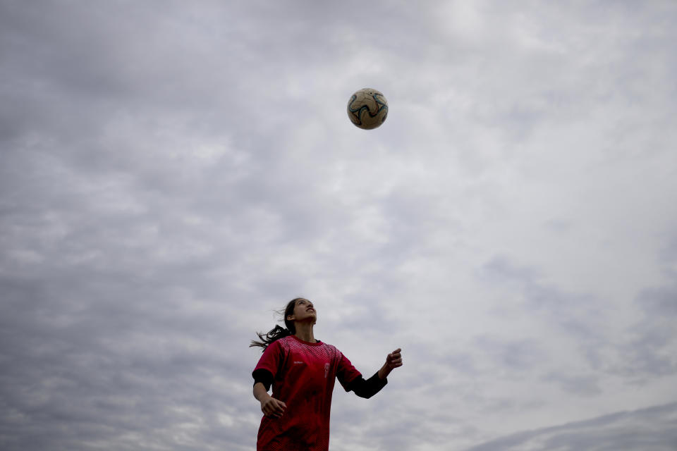 Candelaria Cabrera, a 12-year-old player with the Huracán de Chabas female team, trains on the sidelines of a match as she waits for her team's game to start in Arequito, Argentina, Monday, June 19, 2023. Candelaria, who started playing at age 3 with a ball given by her family, doesn't know whether she will turn professional. But her persistence inspires a new generation of girls who challenge prejudice in soccer loving Argentina. (AP Photo/Natacha Pisarenko)