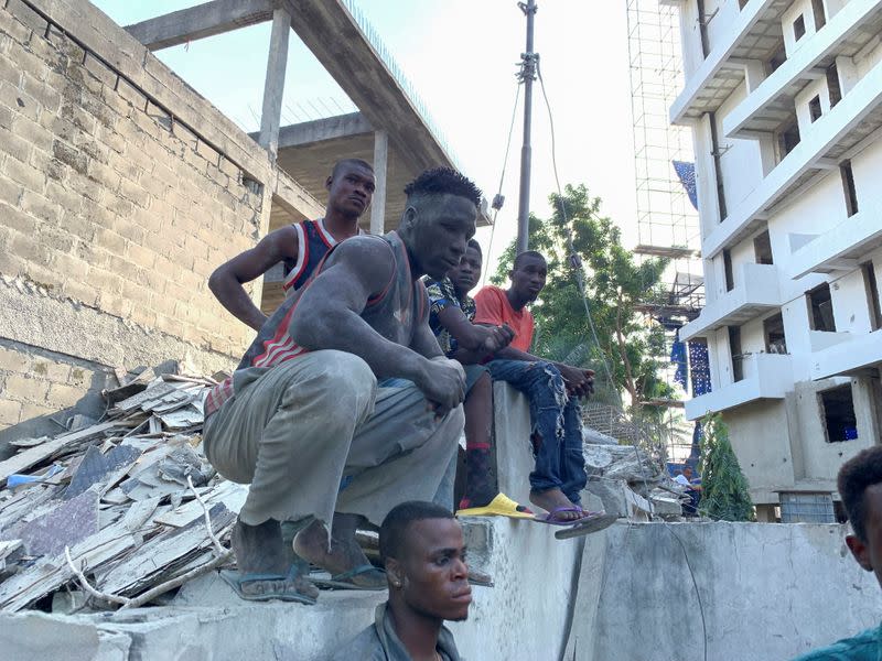 Workers look on at the site of the building collapse in Ikoyi