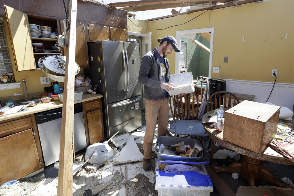 Matthew Alexander looks through a photo album as he helps to salvage items from the damaged home of his parents-in-law Tuesday, April 14, 2020, in Chattanooga, Tenn. Tornadoes went through the area Sunday, April 12. (AP Photo/Mark Humphrey)