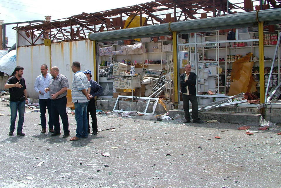 Syrians assess the damage after a bombing attack at a bus station in the coastal town of Tartus, Syria, on May 23, 2016. (SANA via AP)