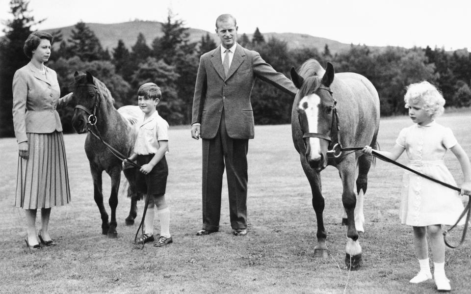 FILE - In this Aug. 15, 1995, photo, Prince Charles and Princess Anne, still in their own pony stage, exercise their Equine pets under the watchful eyes of Queen Elizabeth II and the Duke of Edinburgh during the royal family's summer vacation at Balmoral castle in Scotland. The little prince holds the reins of "William" while his sister guides "Greensleeves." When the hearse carrying Queen Elizabeth II's body pulled out of the gates of Balmoral Castle on Sunday, Sept. 11, 2022, it marked the monarch's final departure from a personal sanctuary where she could shed the straitjacket of protocol and ceremony for a few weeks every year. (AP Photo, File)