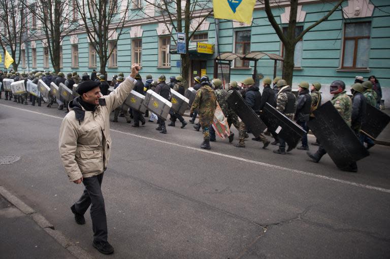 A man raises his fist in the air when meeting a group of anti-government protesters marching in the streets of Kiev, on February 15, 2014