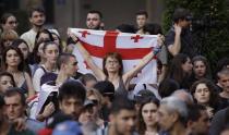 A woman holds a Georgian national flags as opposition demonstrators gather in front of the Georgian Parliament building in Tbilisi, Georgia, Saturday, June 22, 2019. Demonstrators denounced the government Friday as overly friendly to Russia and calling for a snap parliamentary election. (AP Photo/Shakh Aivazov)