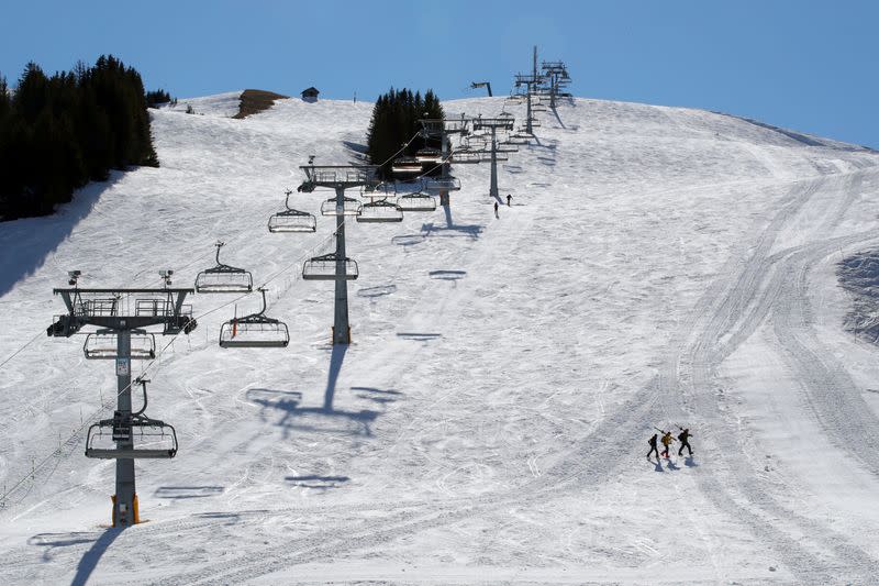 Skiers walk past a closed chair-lift in Les Crosets