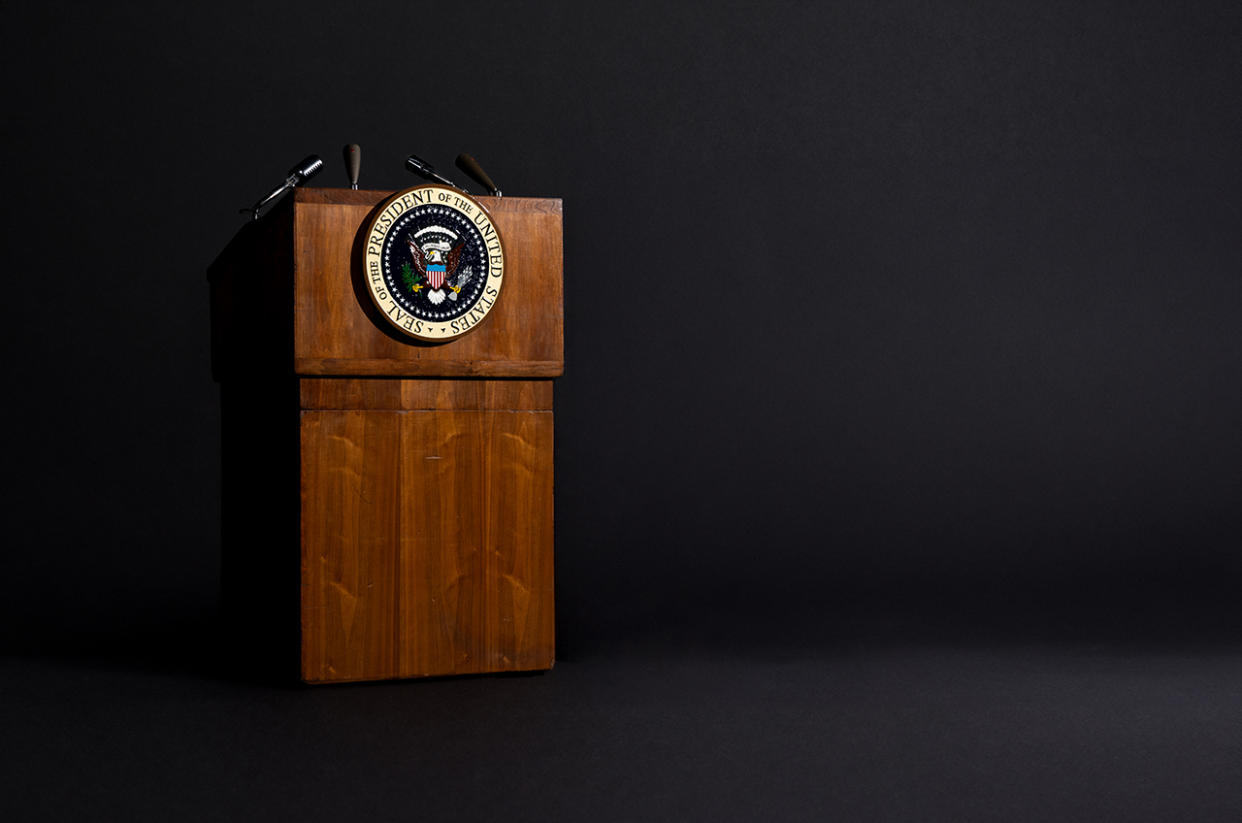  a wooden lectern with the presidential seal stands in front of a black background. 