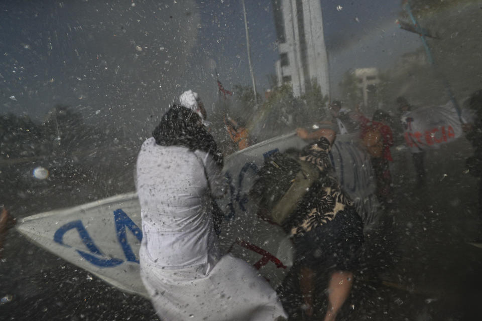 En esta imagen, tomada el 23 de octubre de 2020, una monja, empapada por los cañones de agua empleados por la policía para dispersar a manifestantes antigubernamentales que protestan contra la desigualdad dos días antes de un referéndum sobre la reforma de la Constitución chilena, que data de la dictadura militar de Augusto Pinochet, en Santiago, Chile. En un año marcado por la pandemia y el descontento, los chilenos decidieron por una abrumadora mayoría redactar una nueva Carta Magna que sustituya a la impuesta hace cuatro décadas por Pinochet. (AP Foto/Esteban Félix)