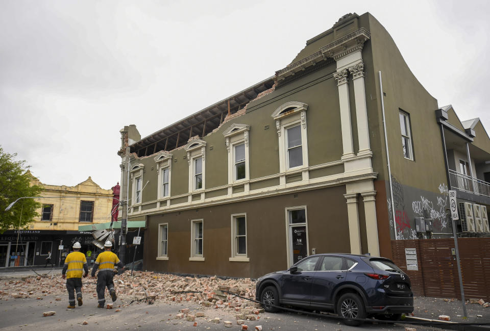 Emergency workers survey damage in Melbourne, Australia, where debris is scattered on a road after part of a wall fell from a building during an earthquake, Wednesday, Sept. 22, 2021. A strong earthquake caused damage in the city of Melbourne in an unusually powerful temblor for Australia, Geoscience Australia said. (James Ross/AAP Image via AP)