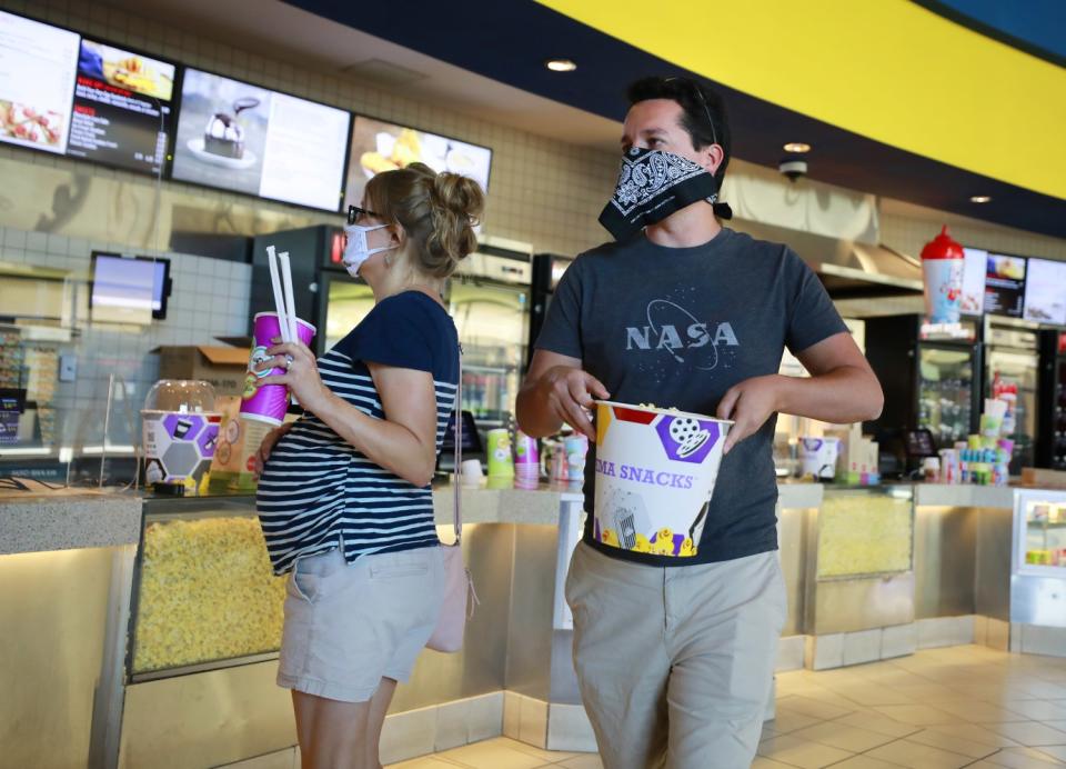 Patrons carry popcorn and drinks into the first showing of "Tenet" at Reading Cinemas Grossmont in La Mesa.