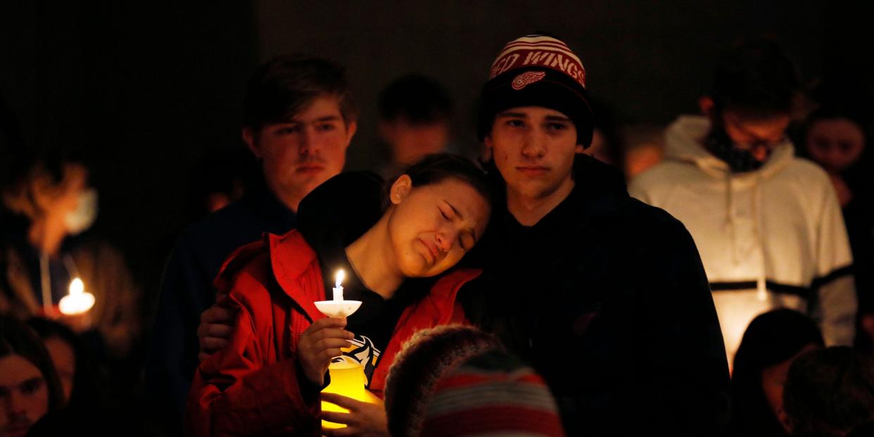 A person becomes emotional as Oxford High students holding candles are asked to stand during a vigil after a shooting at Oxford High School at Lake Pointe Community Church in Lake Orion, Michigan on November 30, 2021. - A 15-year-old student opened fire at his Michigan high school on November 30, killing three teenagers and wounding eight other people before surrendering to police, authorities said, in what was the deadliest US school shooting so far this year. (Photo by JEFF KOWALSKY / AFP) (Photo by JEFF KOWALSKY/AFP via Getty Images)