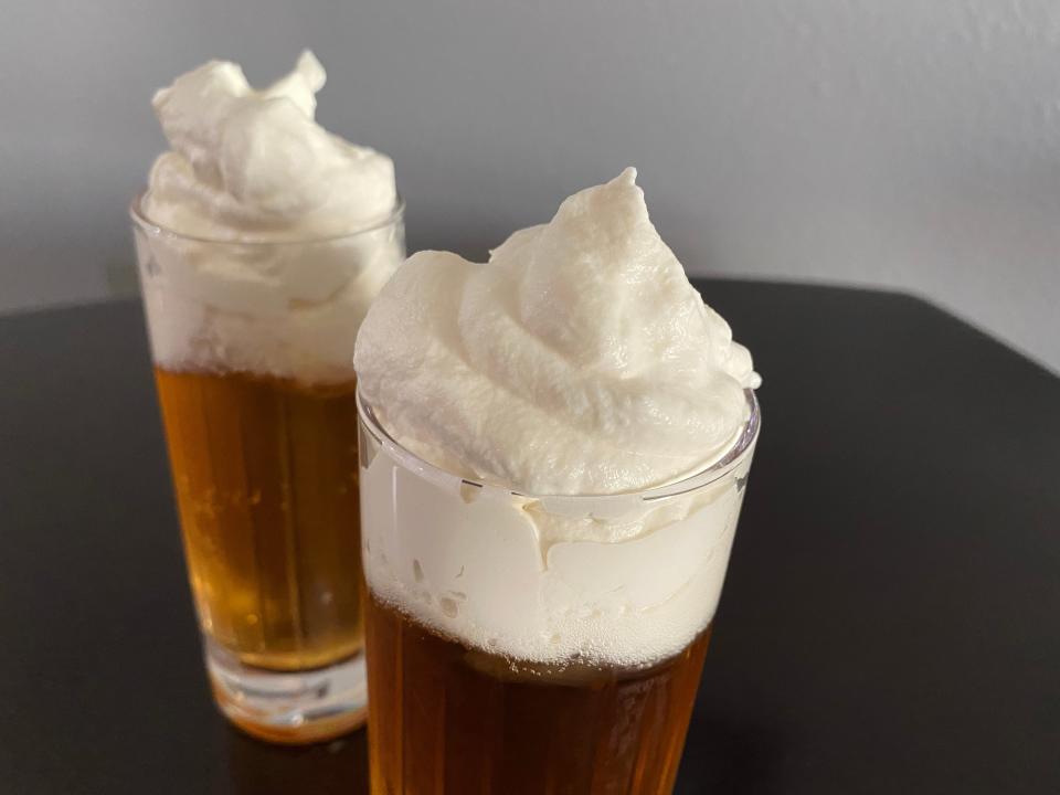 closeup shot of the whipped cream on top of a glass of homemade butterbeer