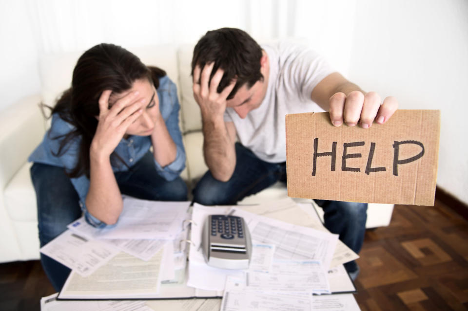 Young couple worried about their finances hold up cardboard 