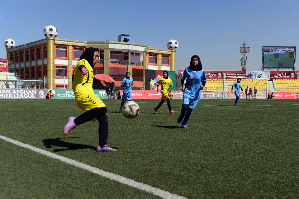 An Afghan female football player of Kabul team (L) vies for the ball against the Herat team during the final match at the Afghanistan Football Federation (AFF) stadium in Kabul on October 3, 2014.  The stands were almost empty at Afghanistan's first women's football league final, but those supporters who did turn up were determined to mark the occasion with noisy chants and cheers as Kabul came out 5-1 winners.   The women's four-team league was a ground-breaking tournament in Afghanistan, and was held in parallel with the Afghan Premier League (APL), a competitive and well-established men's event now in its third year.   AFP PHOTO / WAKIL KOHSAR        (Photo credit should read WAKIL KOHSAR/AFP via Getty Images)