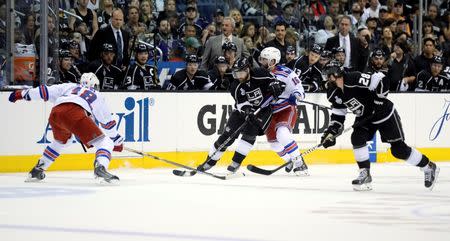 Jun 13, 2014; Los Angeles, CA, USA; Los Angeles Kings right wing Justin Williams (14) controls the puck between New York Rangers right wing Derek Dorsett (15) and defenseman Marc Staal (18) during the first period in game five of the 2014 Stanley Cup Final at Staples Center. Gary A. Vasquez-USA TODAY Sports