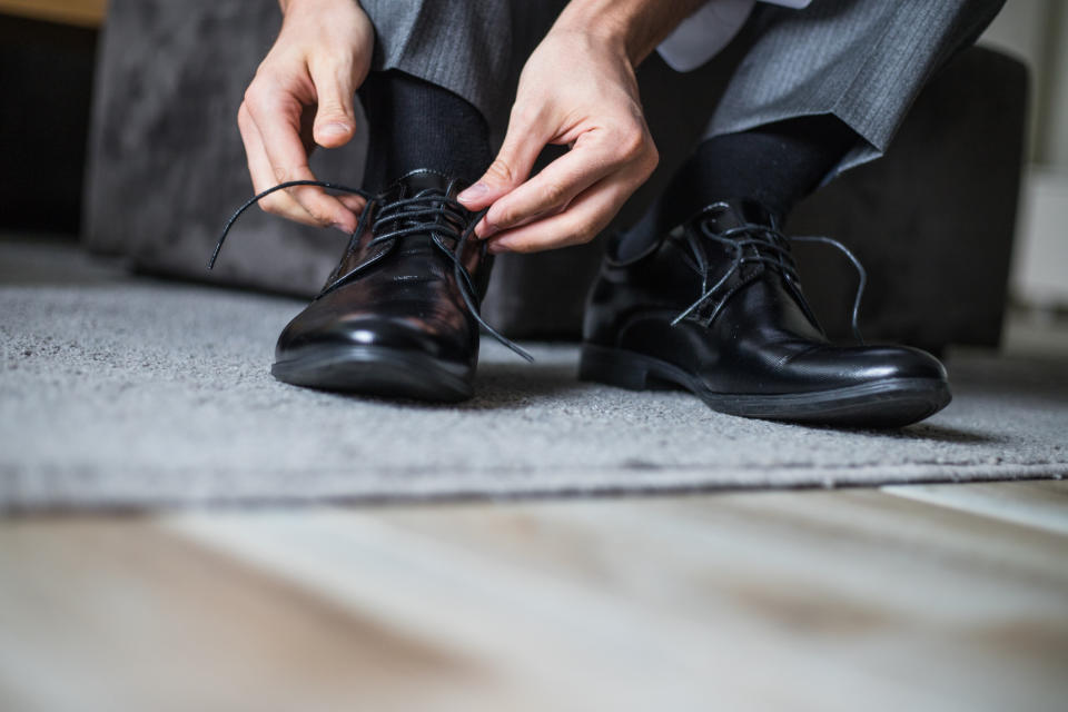 Person tying the laces of polished dress shoes, preparing for a formal event