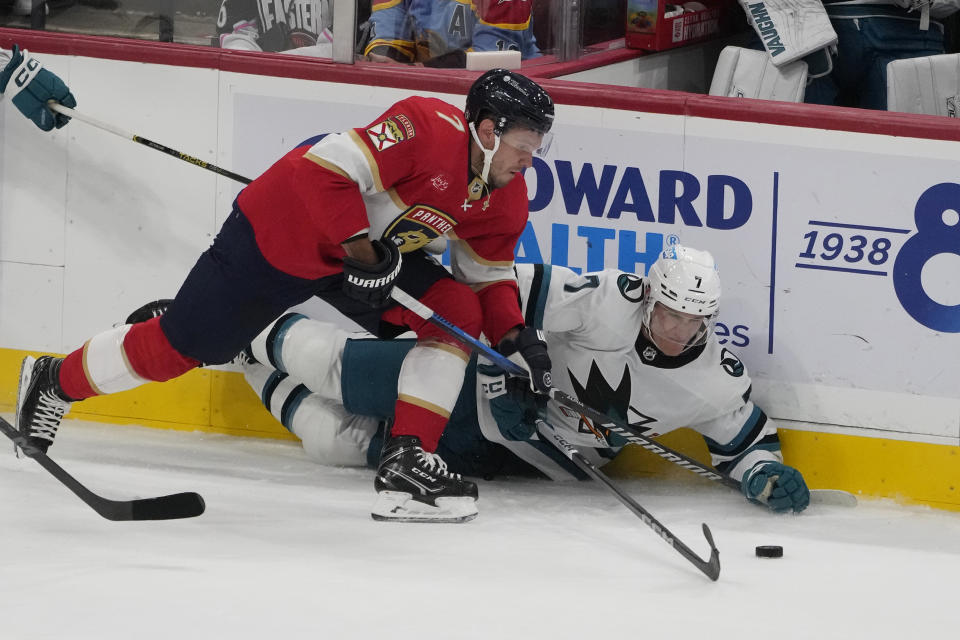 Florida Panthers defenseman Dmitry Kulikov (7) and San Jose Sharks center Nico Sturm (7) go after the puck during the first period of an NHL hockey game, Tuesday, Oct. 24, 2023, in Sunrise, Fla. (AP Photo/Marta Lavandier)