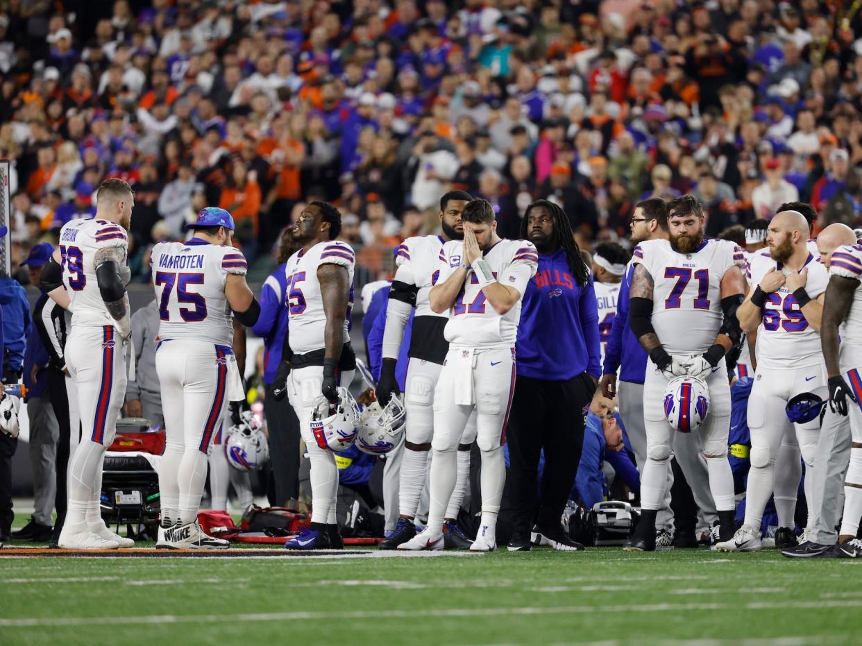 Buffalo Bills players surround a medical team tending to Damar Hamlin after his cardiac arrest on the football field.