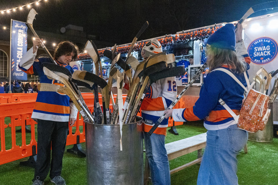 New York Islanders fans peruse a container of practice hockey sticks used by Islanders players at the grand opening of The Park at UBS Arena in Elmont, N.Y., Friday, Dec. 29, 2023. (AP Photo/Peter K. Afriyie)