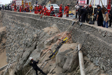 Rescue workers carry victims after a bus crashed with a truck and careened off a cliff along a sharply curving highway north of Lima, Peru, January 3, 2018. REUTERS/Guadalupe Pardo