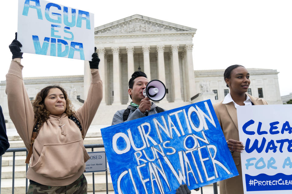 FILE - Bethsaida Sigaran, left, of Baltimore, her brother Jaime Sigaran, with American Rivers, and Thea Louis, with Clean Water Action, join supporters of the Clean Water Act as they demonstrate outside the Supreme Court, Monday, Oct. 3, 2022, in Washington, as the court begins arguments in Sackett v. Environmental Protection Agency (EPA). The Supreme Court on Thursday, May 25, 2023, made it harder for the federal government to police water pollution in a decision that strips protections from wetlands that are isolated from larger bodies of water. (AP Photo/Jacquelyn Martin, File)