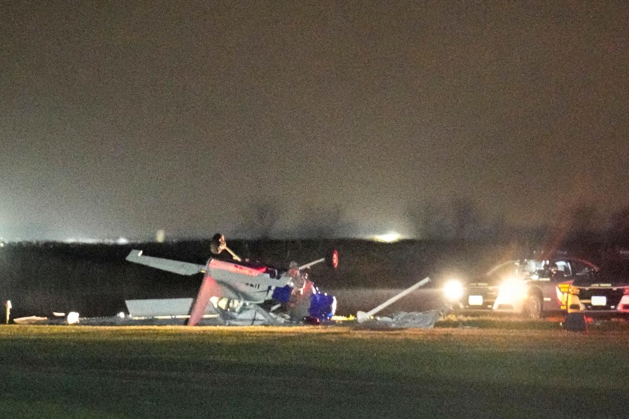 A small plane that crashed in a field Tuesday night near the end of the runway at Madison County Airport is illuminated by lights from law enforcement vehicles on Tuesday night. A Columbus man and hotelier learning to fly and the owner-pilot from Alabama were killed in the crash.