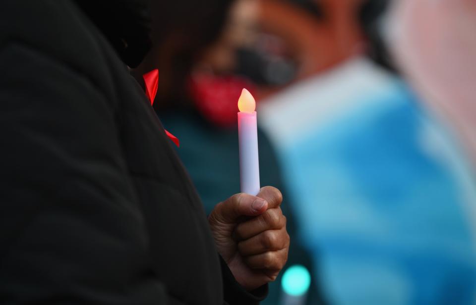A woman holds a candle in commemoration of World AIDS Day and Covid-19 deaths at NYC Health + Hospitals/Woodhull, on December 1, 2020 in New York City. (Photo by Angela Weiss / AFP) (Photo by ANGELA WEISS/AFP via Getty Images)