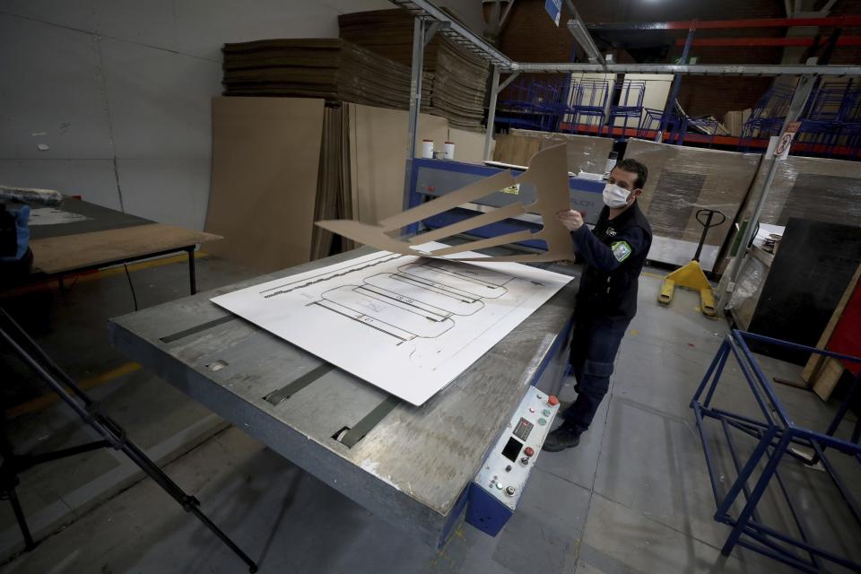 A worker at a company that designs packaging for product displays assembles a cardboard box designed to serve as both a hospital bed and a coffin, intended for COVID-19 patients, in Bogota, Colombia, Friday, May 8, 2020. Owner Rodolfo Gomez said he plans to donate the first units to Colombia's Amazonas state, and that the company will sell others to small hospitals for 87 dollars. (AP Photo/Fernando Vergara)