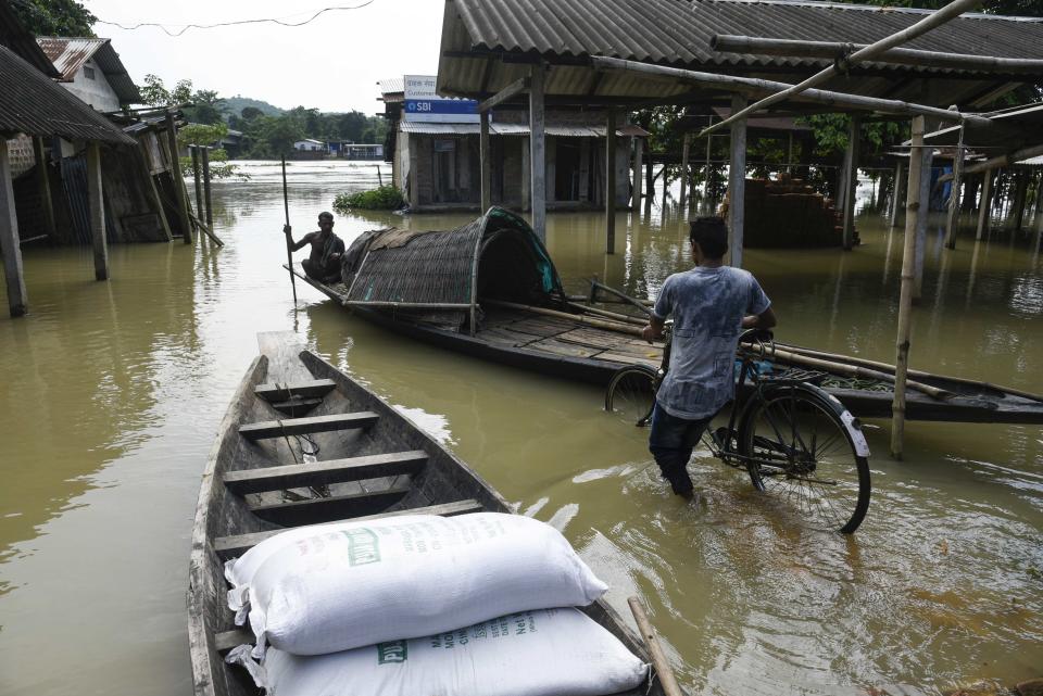 Villager uses a country boat to move across a flooded locality in Morigaon district of Assam in India on July 13, 2020. (Photo by David Talukdar/NurPhoto via Getty Images)