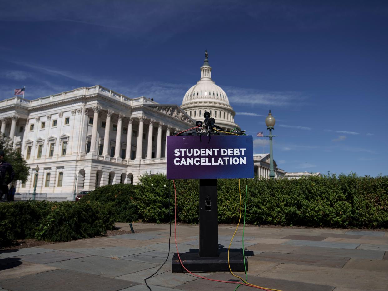 The words "Student debt cancellation" appear on an empty lectern placed in front of the US capitol
